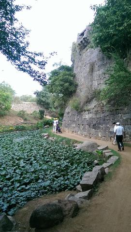 Golfers walk along a fort wall between tees