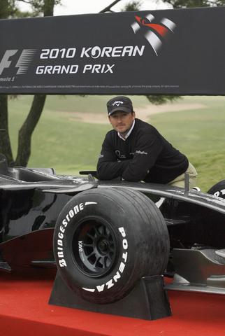 Graeme McDowell of Northern Ireland poses with the F1 car